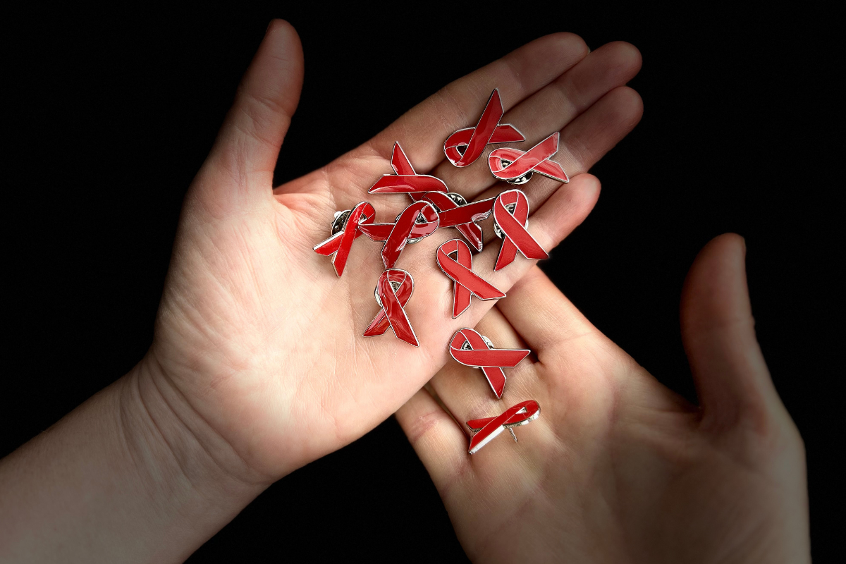 Red ribbon pin badges in a pair of palms
