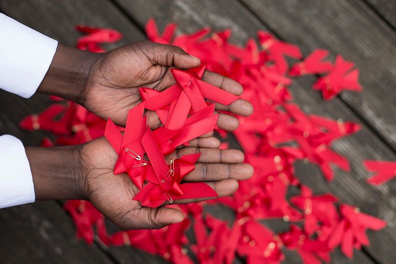 Open palms holding red ribbons.