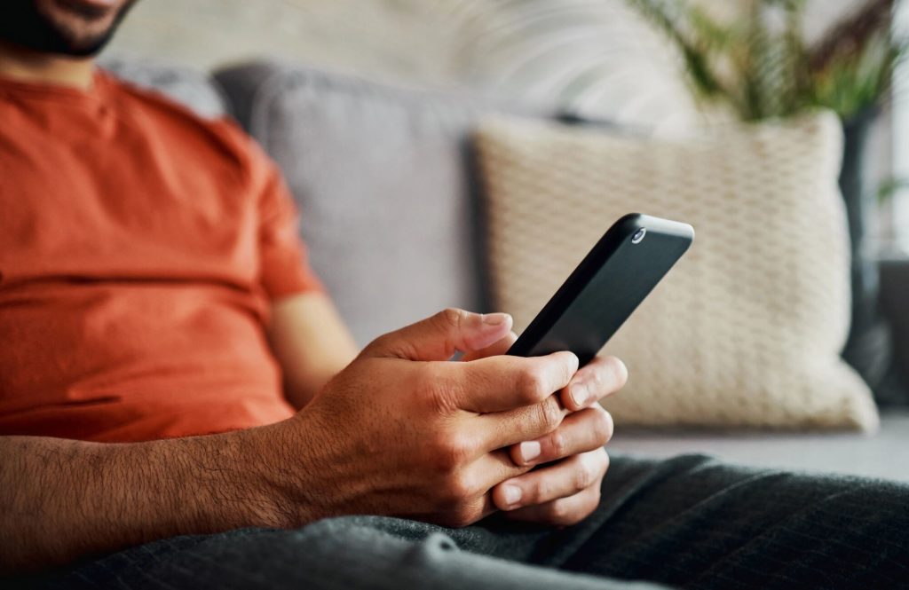 A man sits on a sofa looking at his phone.